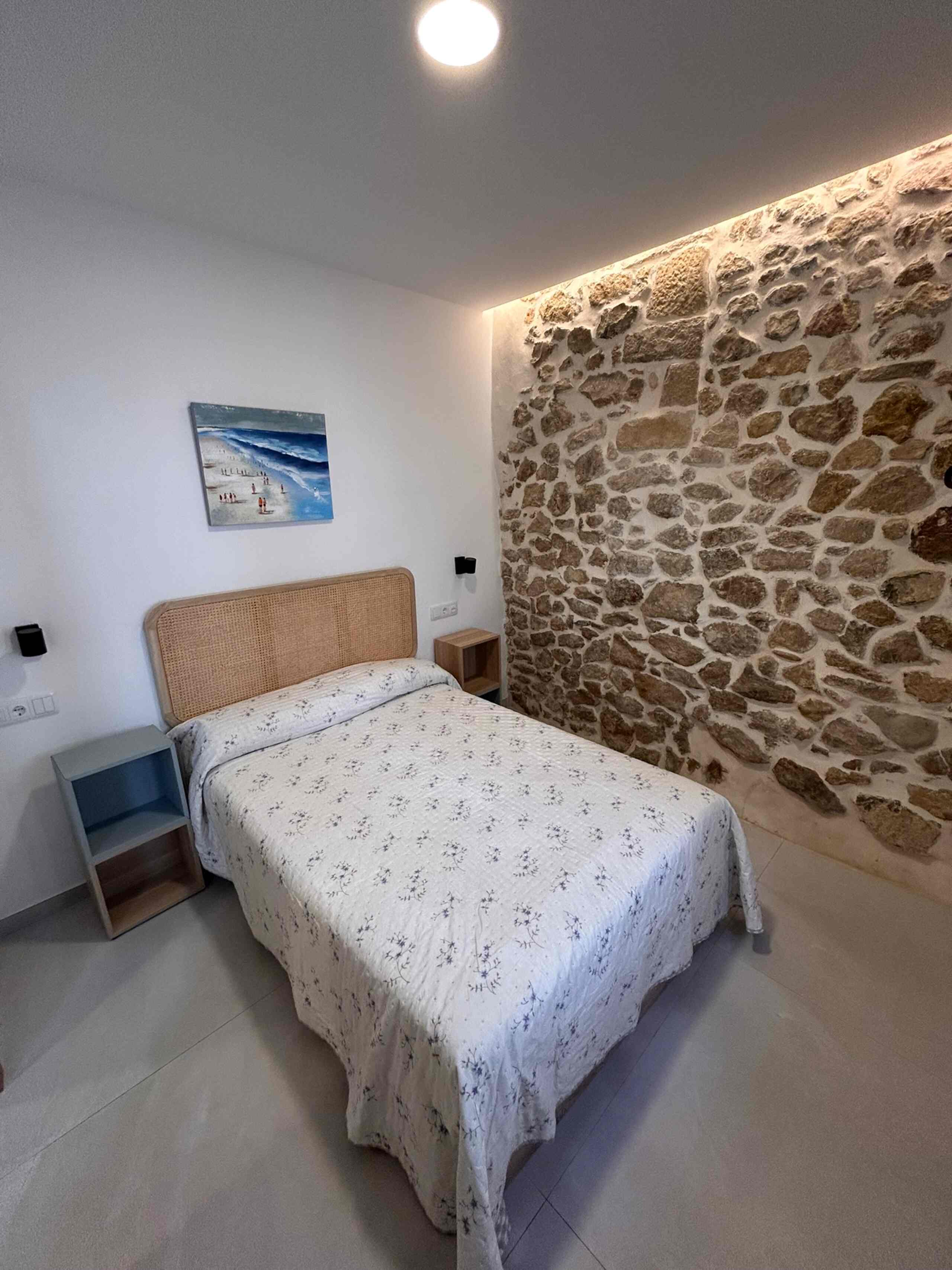 Dormitorio de alojamiento turístico con pared de piedra
