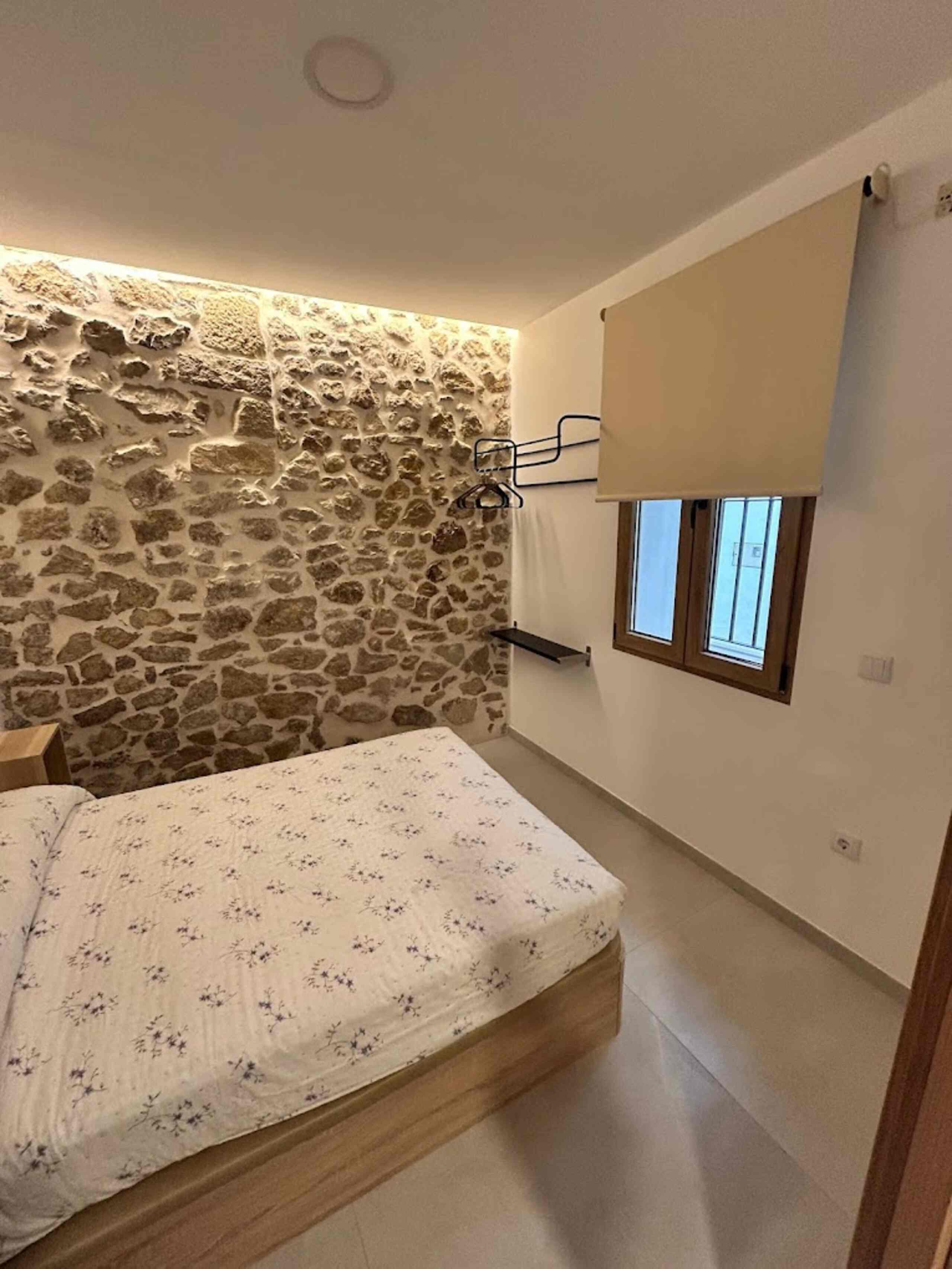 Dormitorio de alojamiento turístico con pared de piedra